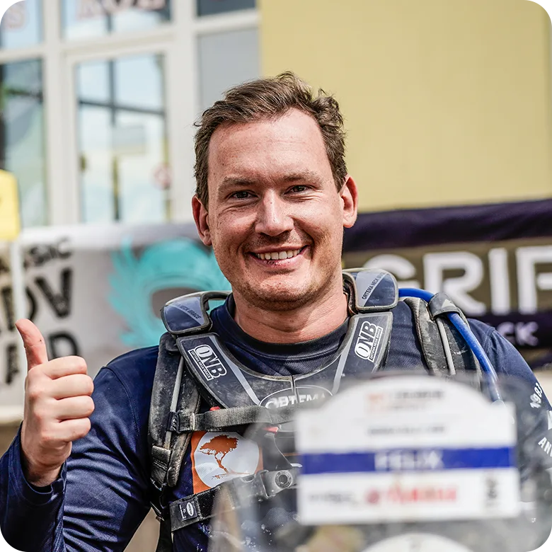 Portrait Bild Motorradfahrer mit Daumen nach oben Mann mit Helm und Motorradkleidung zeigt Daumen hoch und lächelt stolz in die Kamera.